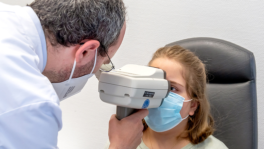 Der Augenarzt untersucht das Auge eines Mädchen